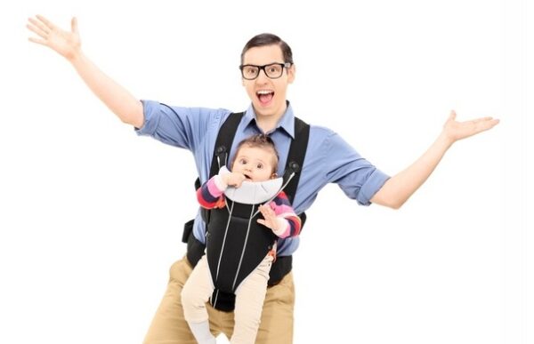 Happy man with baby facing forwards in a sling