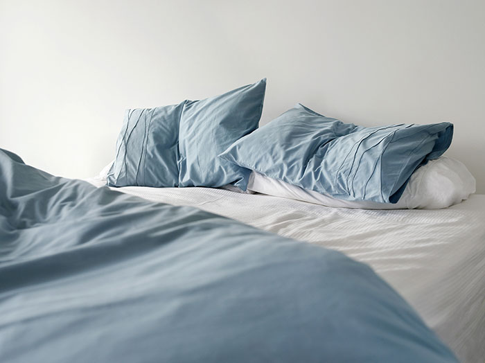An unmade bed with blue sheets