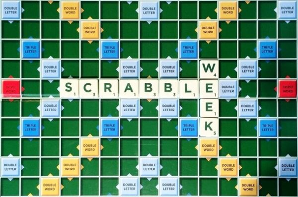 Scrabble tiles on board spelling out SCRABBLE WEEK