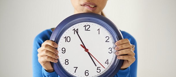 A woman holding a clock looking worried