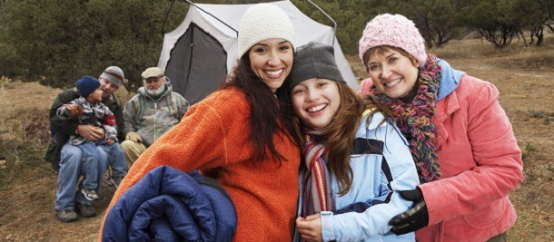 A family smiling outside their tent