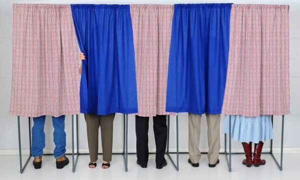 People in voting booths behind curtains