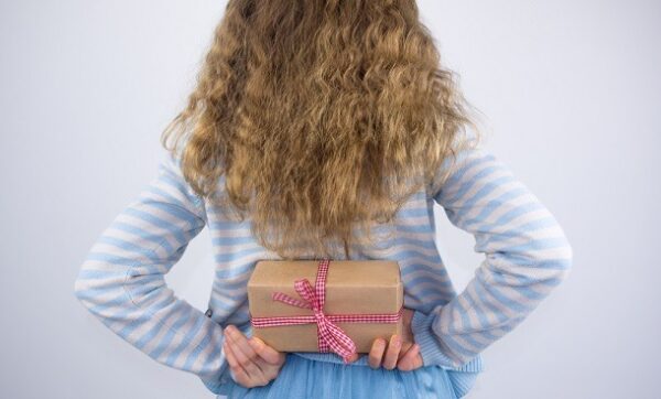 A small girl holding a present behind her back