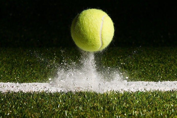 A tennis ball hitting off chalk line