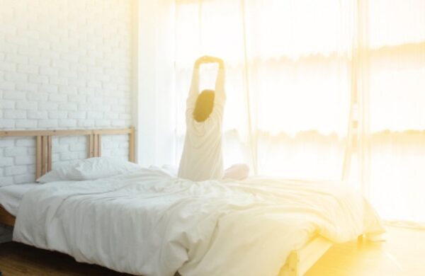 woman stretching on her bed in strong sunlight