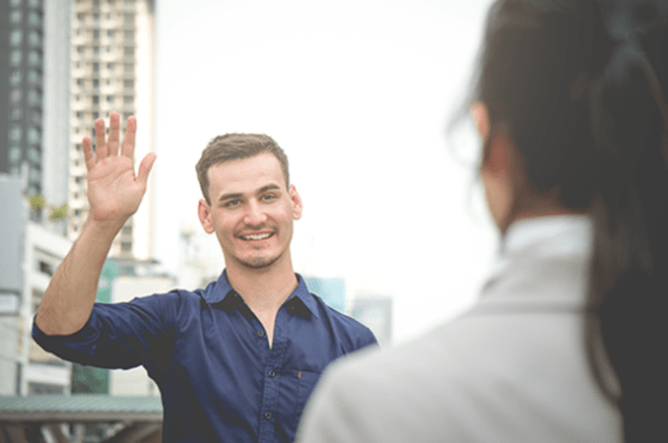 a man meeting a woman, raising his hand in greeting