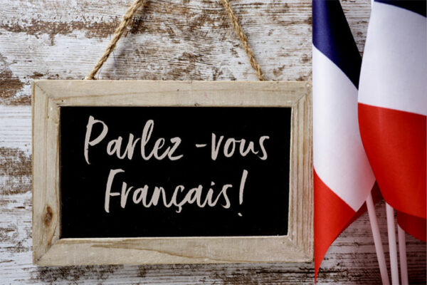 Small blackboard with Parlez-vous Francais written on it, with French flags beside it.